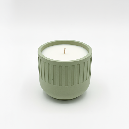Green candle holder with a white candle inside on a white background